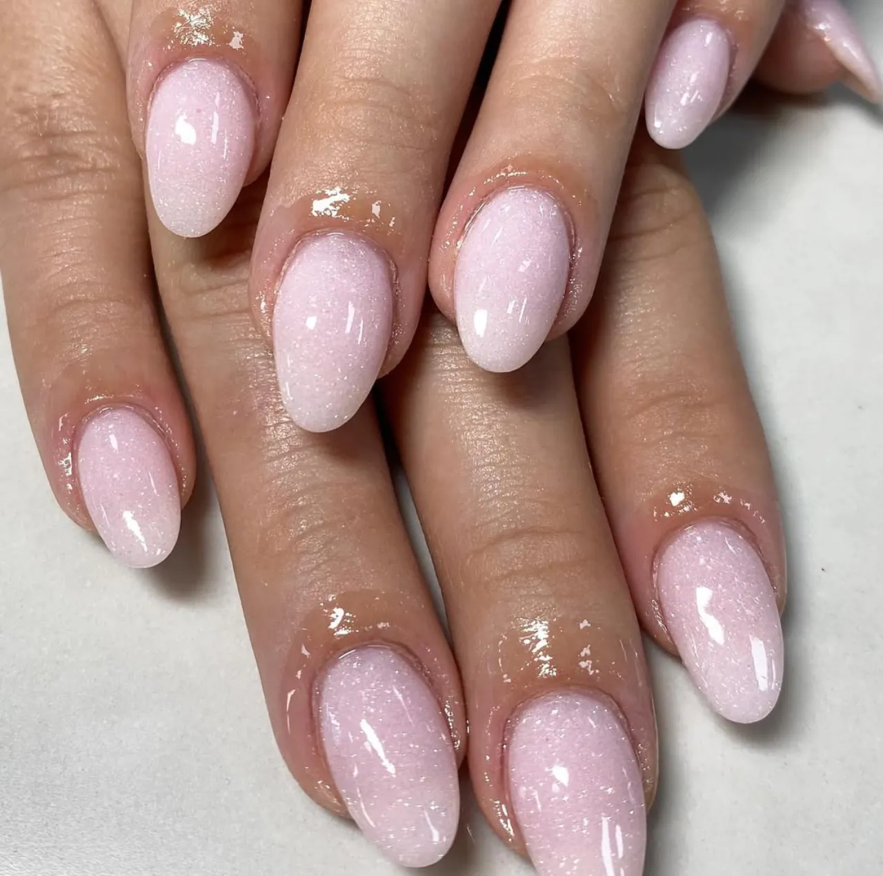 Diseños de uñas acrílicas rosas con glitter sutil y forma almendrada.