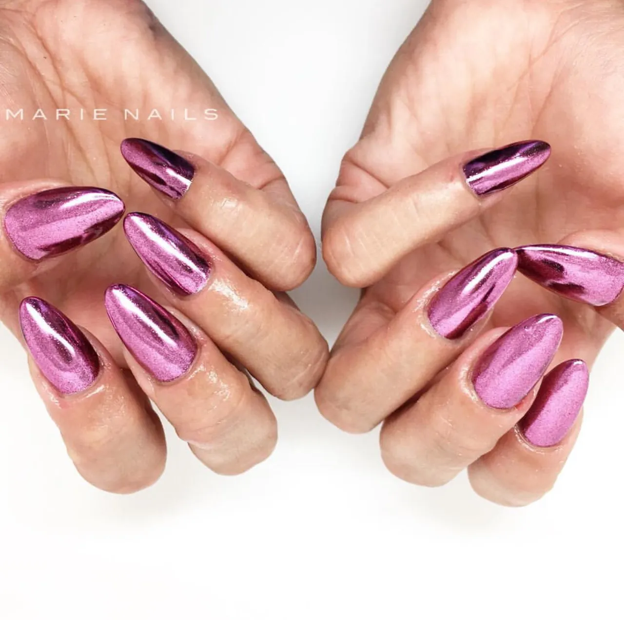 Diseños de uñas acrílicas rosas metálicas con acabado cromado y forma almendrada.
