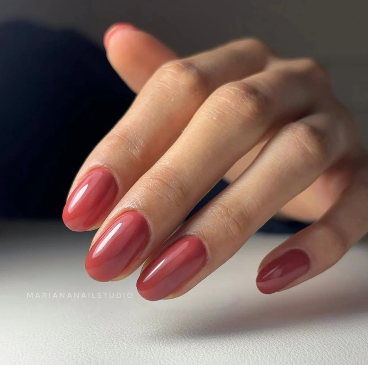 Diseños de uñas acrílicas color terracota con acabado brillante y forma almendrada.