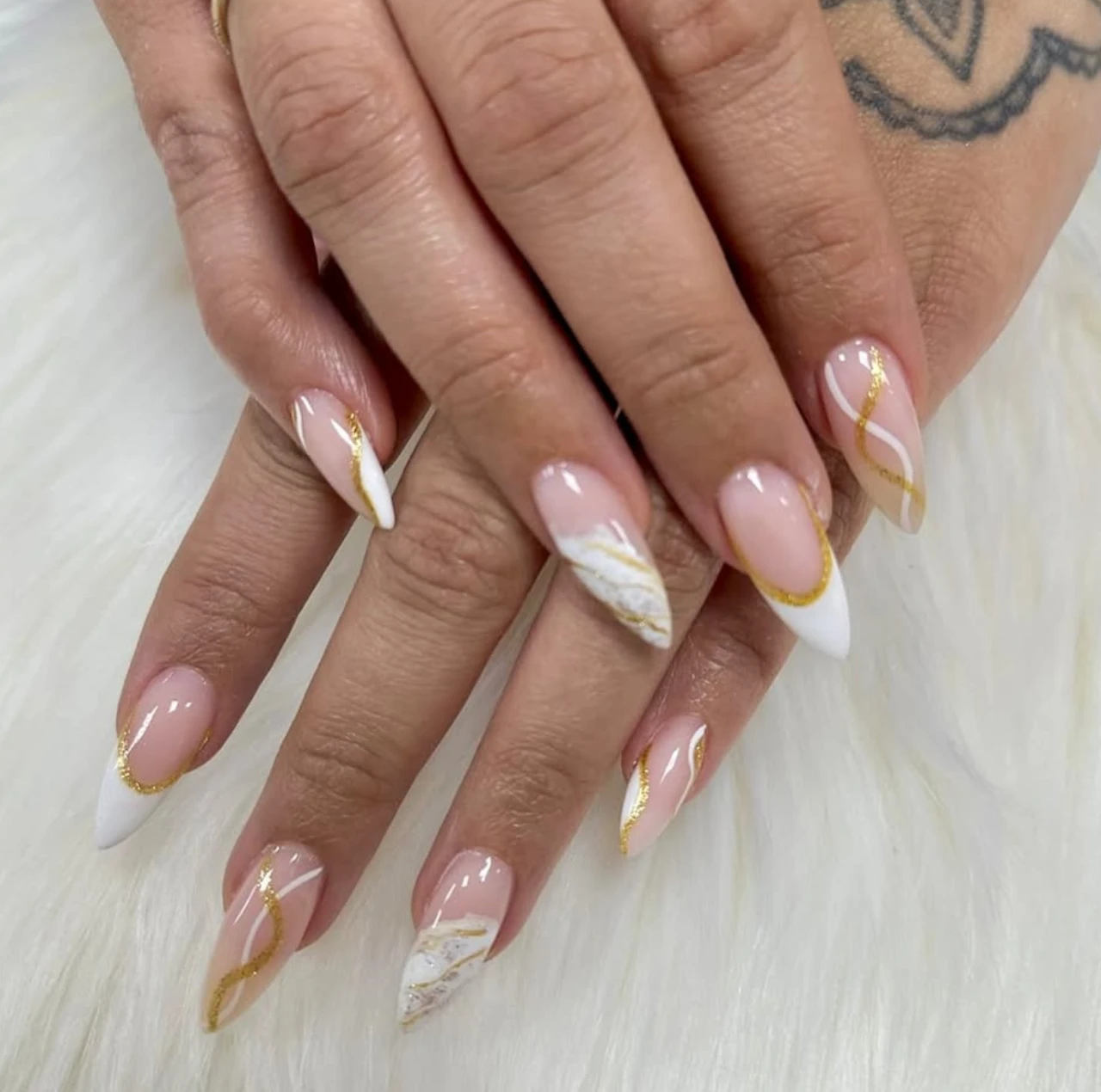 Diseños de uñas acrílicas abstractas con detalles en dorado, blanco y nude.