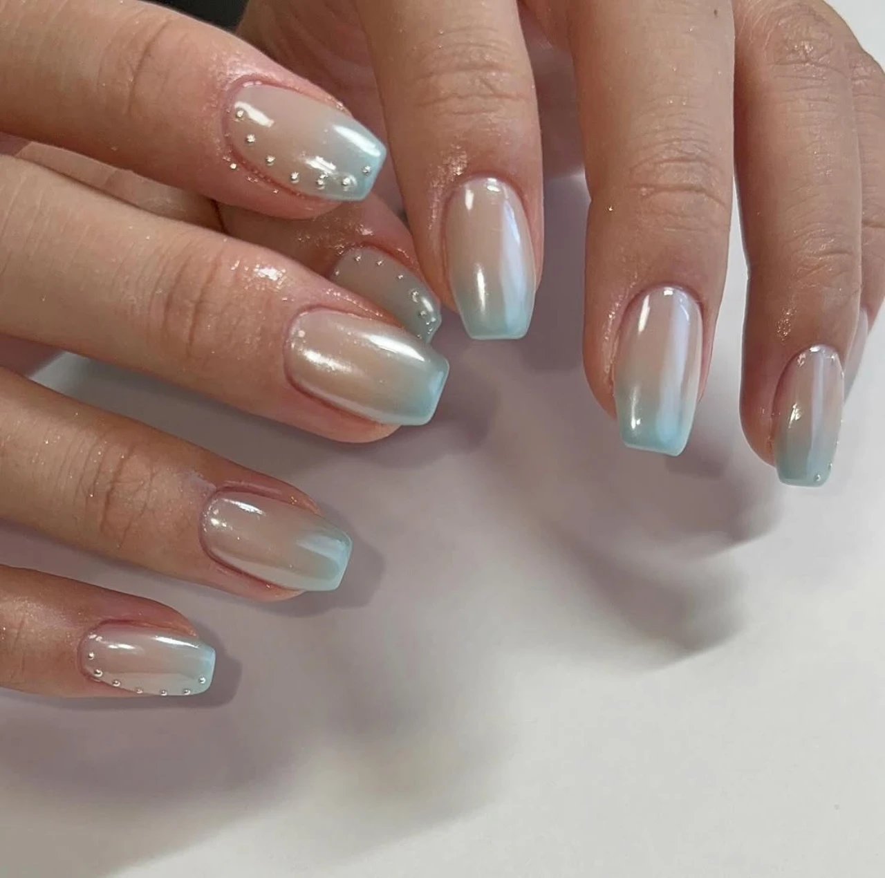 Diseños de uñas acrílicas degradadas azules metalizadas con efecto perlado.