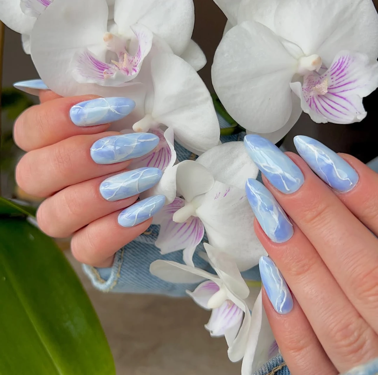Diseños de uñas acrílicas mármol azul con vetas blancas en acabado brillante.