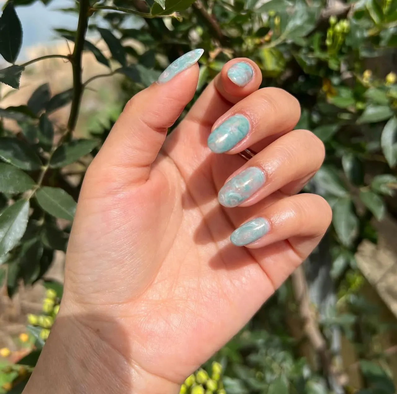 Diseños de uñas acrílicas con efecto mármol en tonos turquesa y verde agua.
