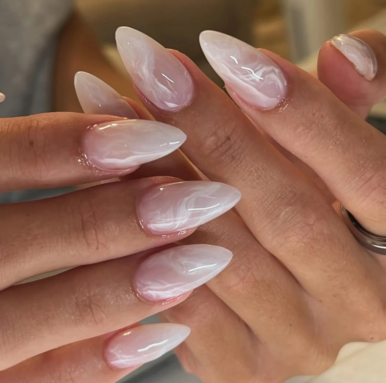 Diseños de uñas acrílicas mármol en tonos blancos y rosados con acabado brillante.