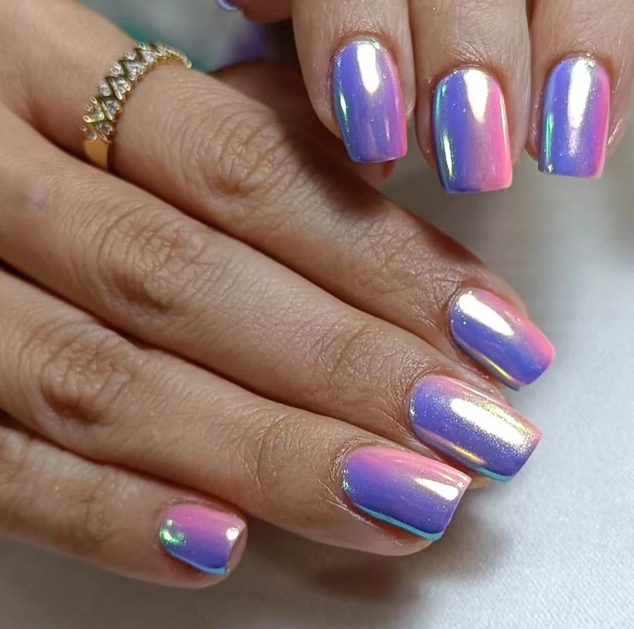 Diseños de uñas acrílicas tornasoladas con acabado espejo en tonos rosa y morado.