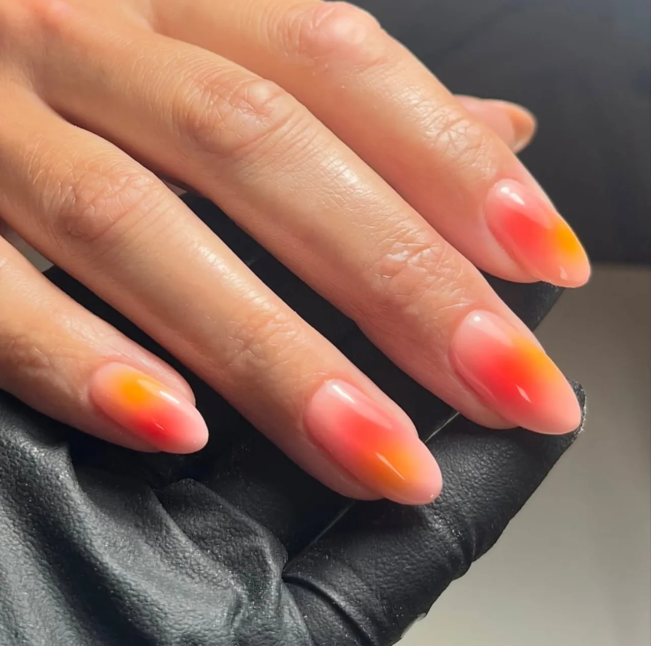 Efecto aura en uñas con tonos cálidos tipo atardecer en degradado suave.