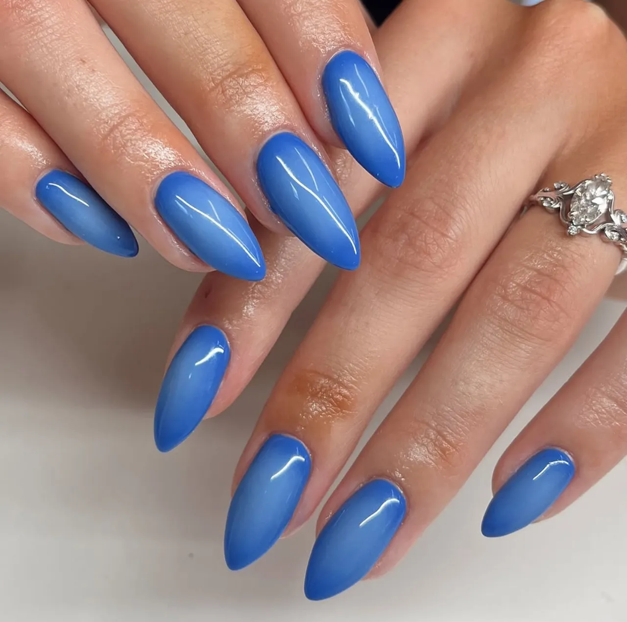 Efecto aura en uñas en tonos azules con acabado degradado y brillante.