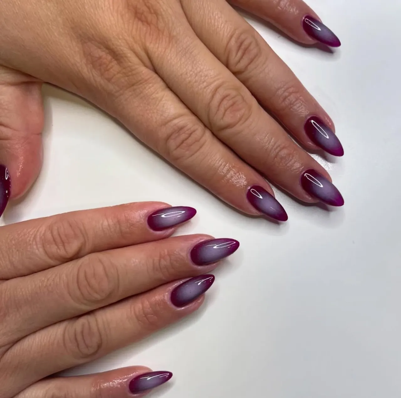 Efecto aura en uñas con tonos burgundy y lila en acabado brillante y difuminado.