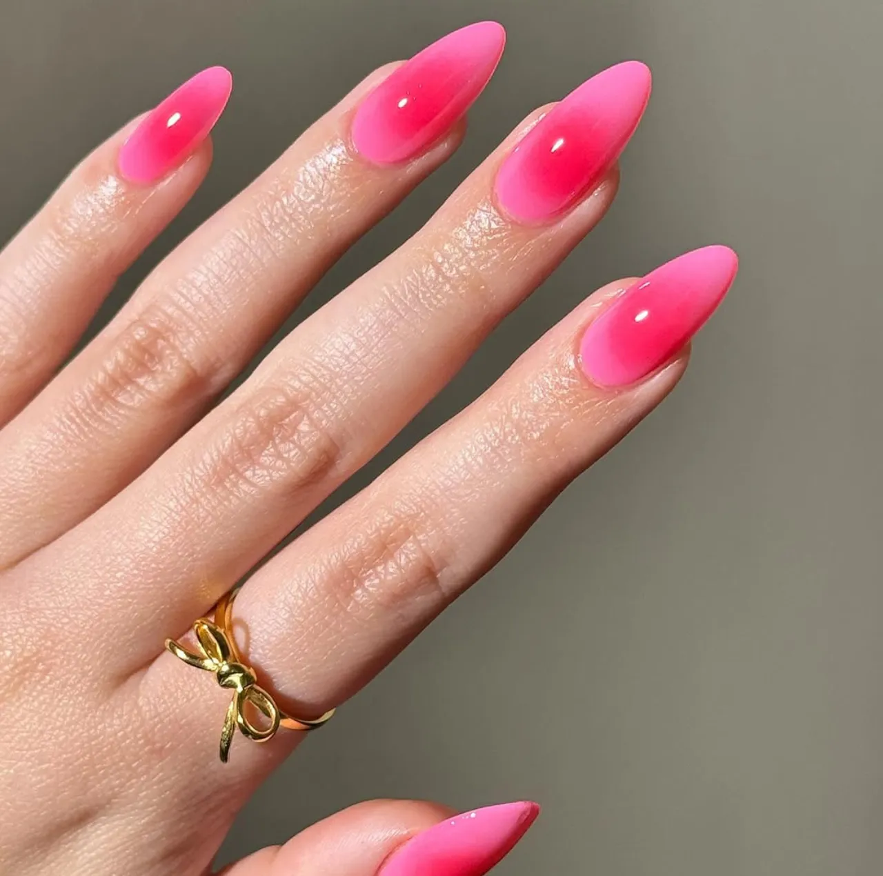 Efecto aura en uñas con tono fresa brillante y acabado degradado en forma estileto.