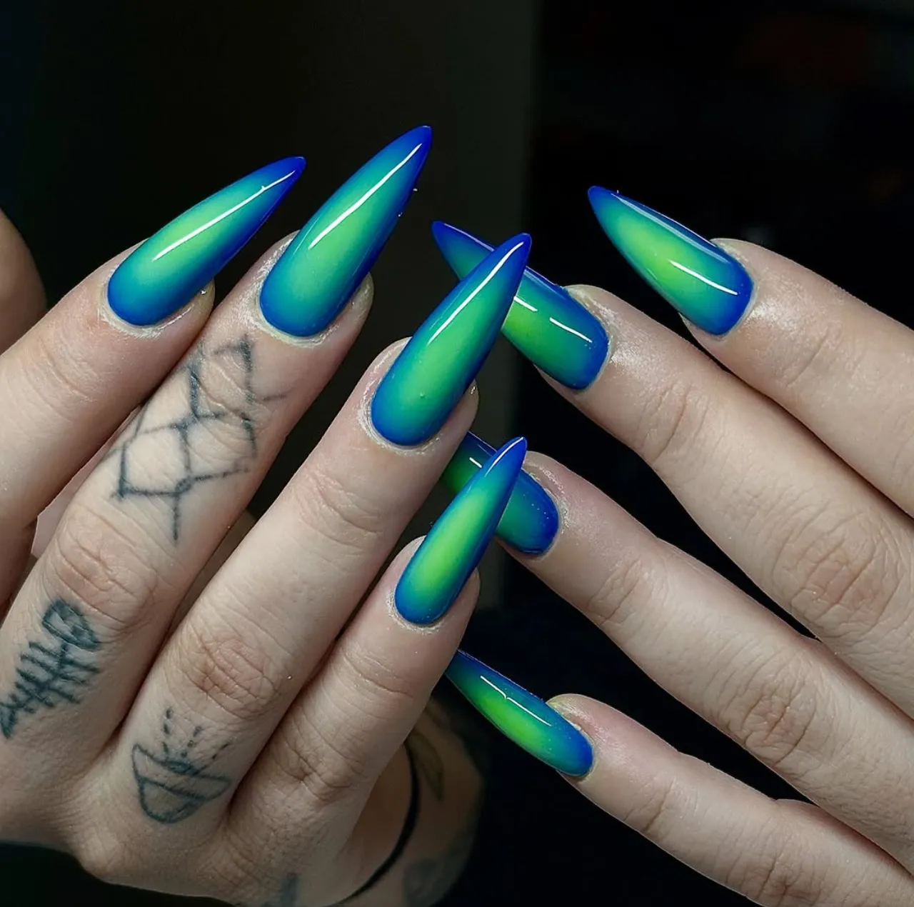 Efecto aura en uñas con degradado verde y azul en uñas largas estilo estileto.