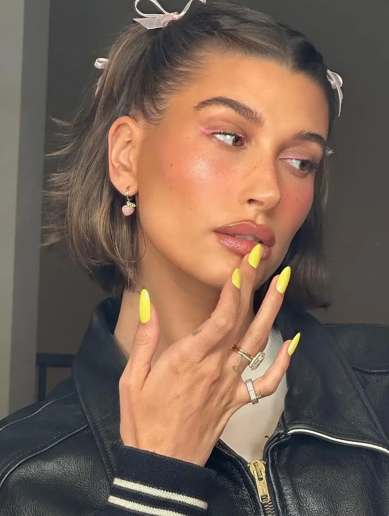 Hailey Bieber posing with bright yellow buttercup celebrity nails and chic style