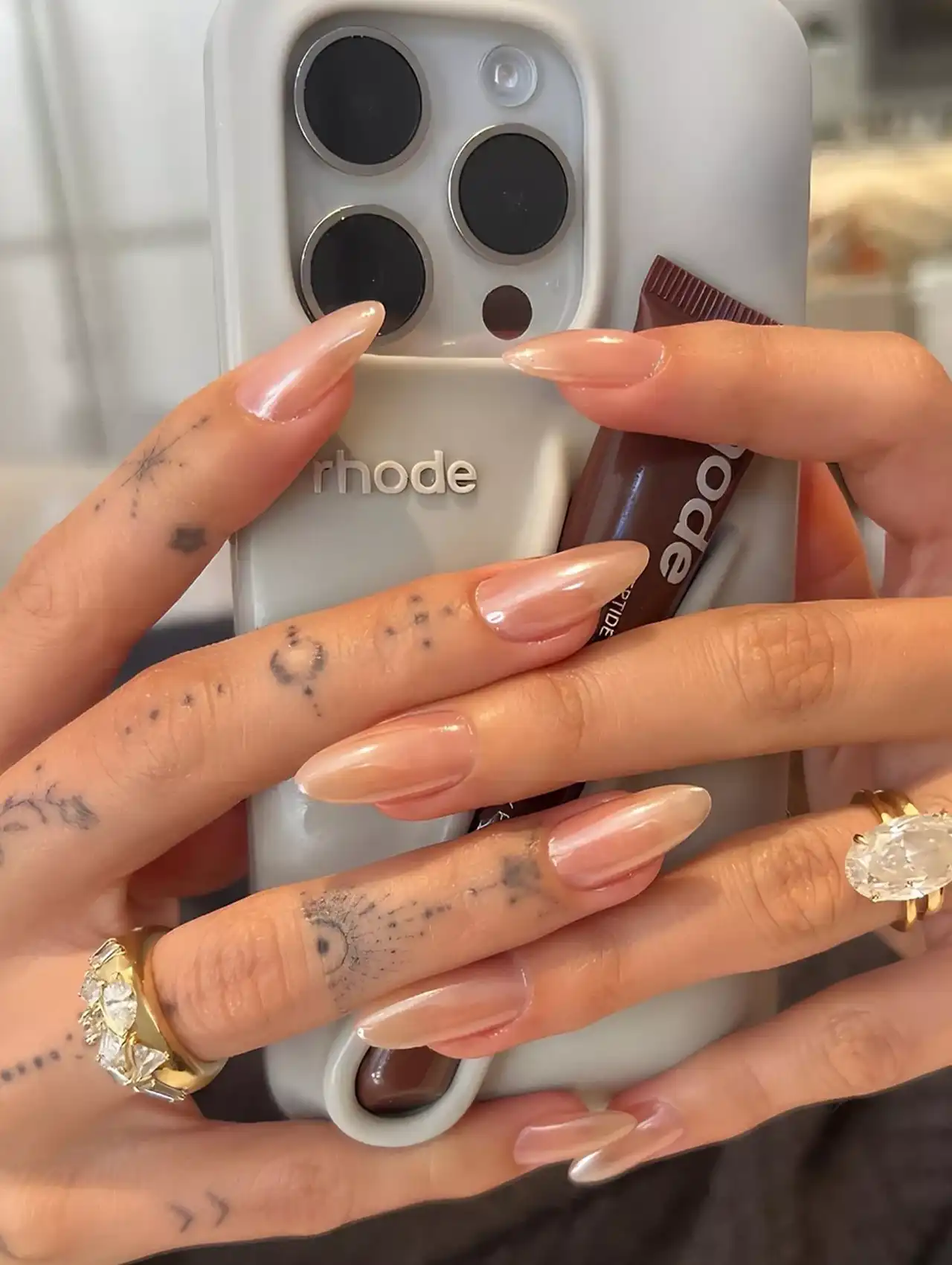 Close-up of Hailey Bieber’s signature glazed donut celebrity nails with nude shimmer