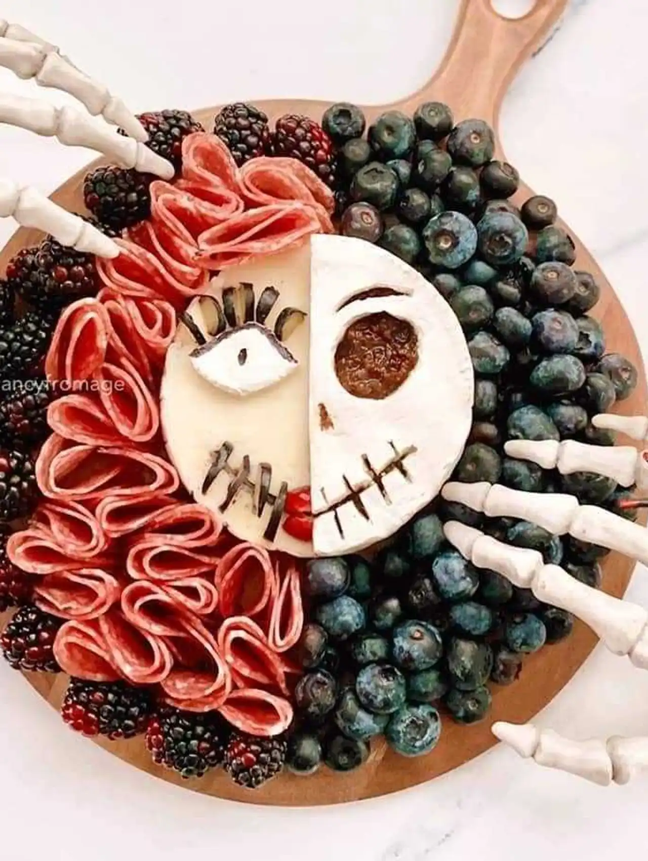 Nightmare Before Christmas inspired halloween charcuterie board with half skull cheese face, berries, and salami.