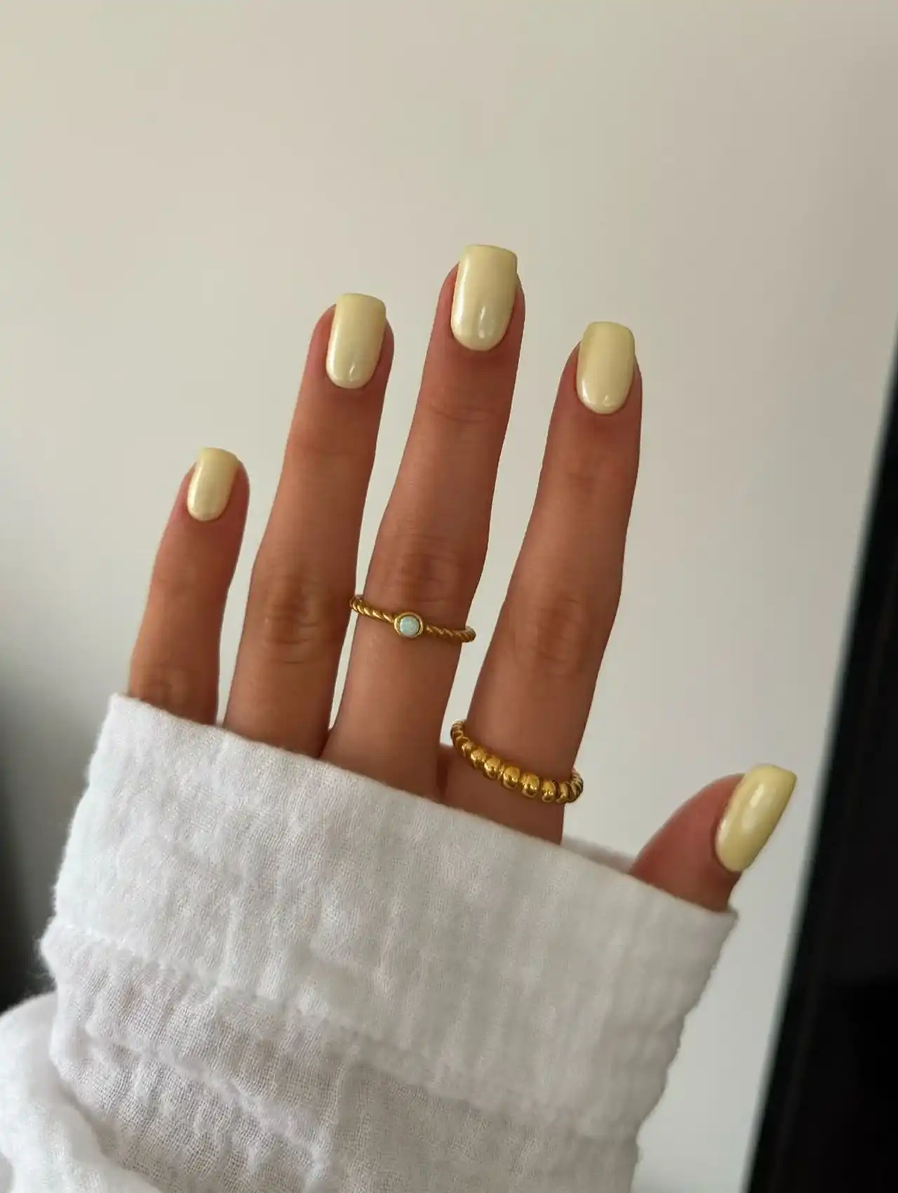Hand with soft pastel yellow nails in a glossy finish for summer nail designs