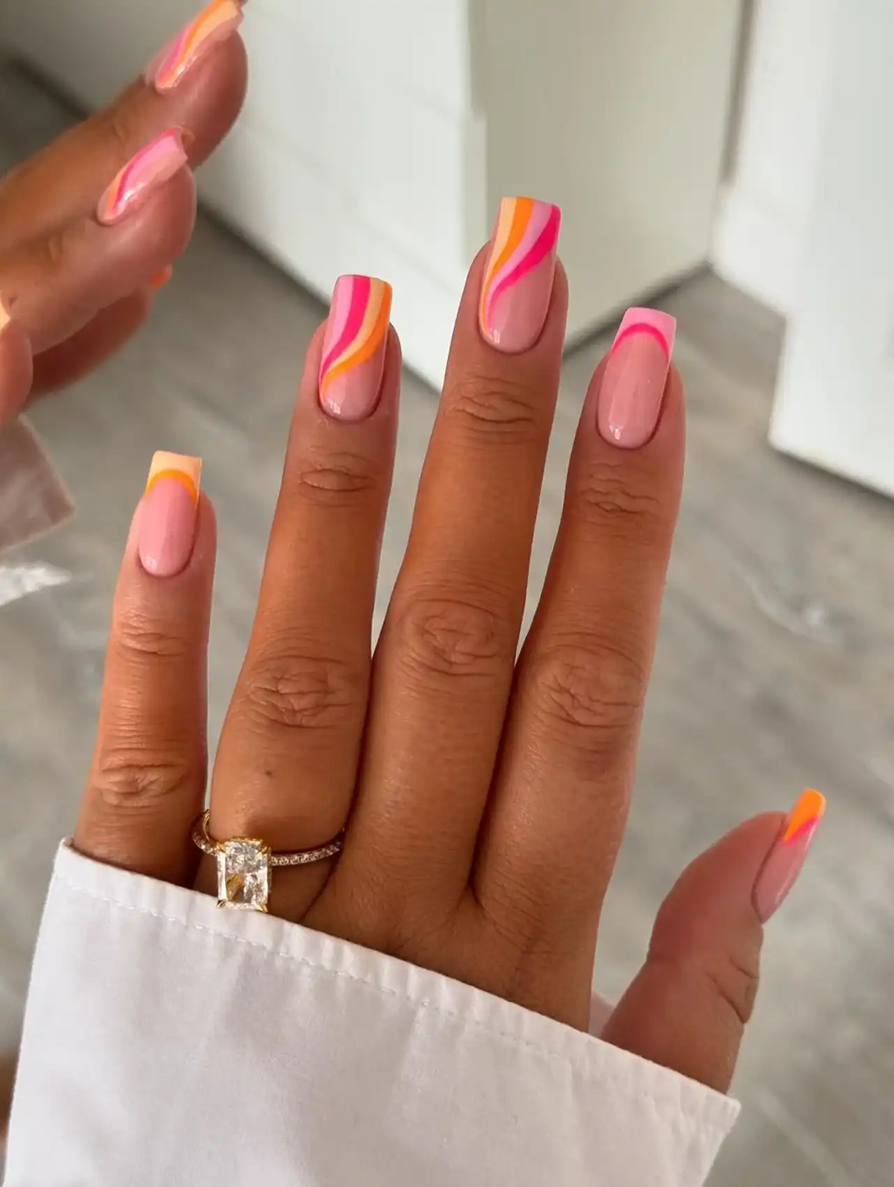 Pink and orange swirl nail art on a nude base for trendy summer nail designs