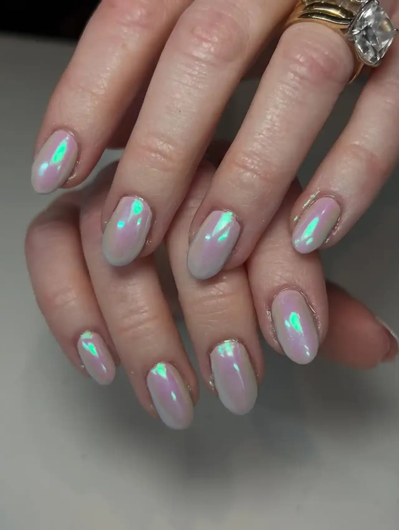 Soft nude base nails with green reflective chrome showcasing aurora nail design ideas