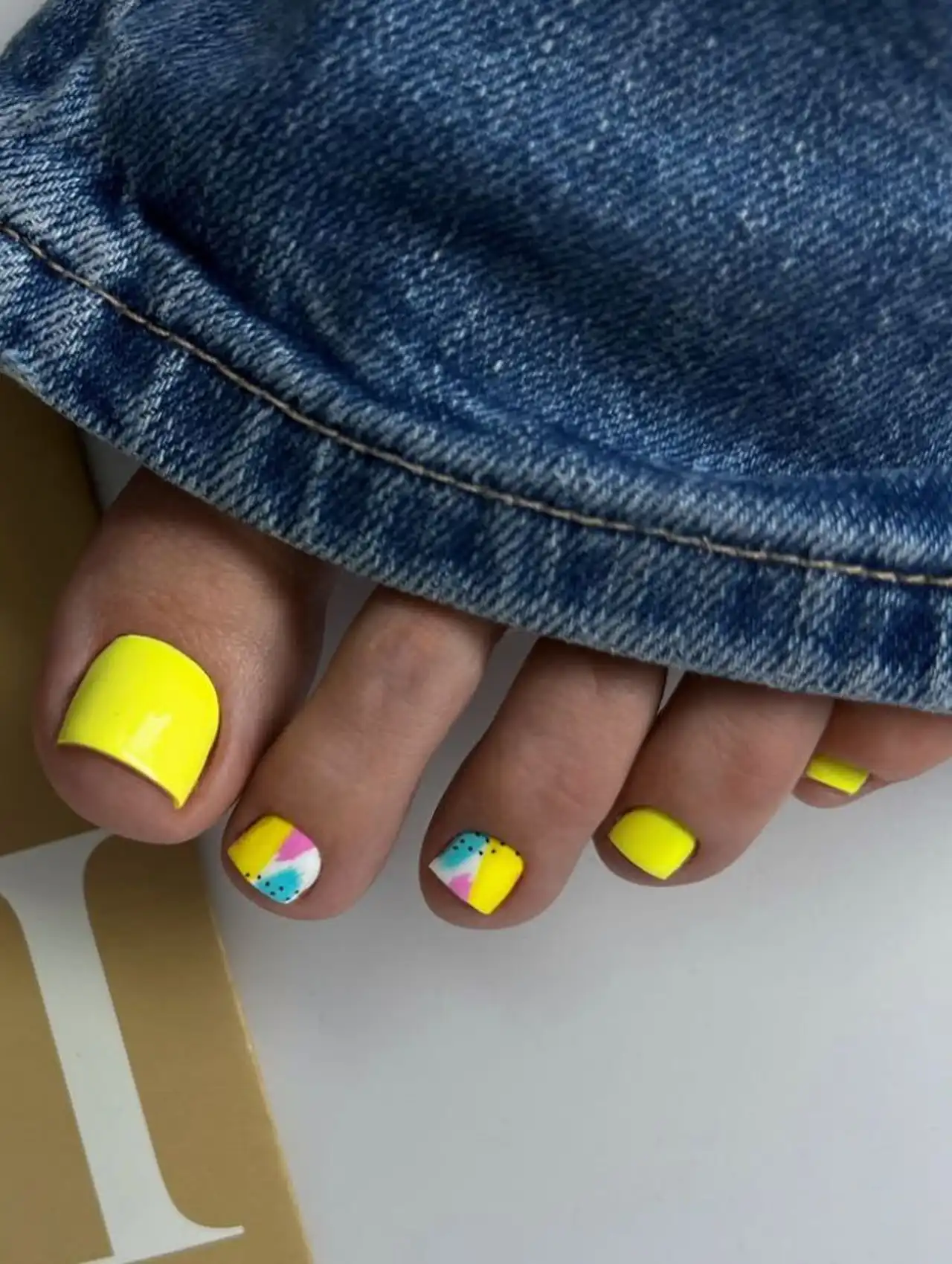 Yellow summer toe nail design with geometric multicolor accents