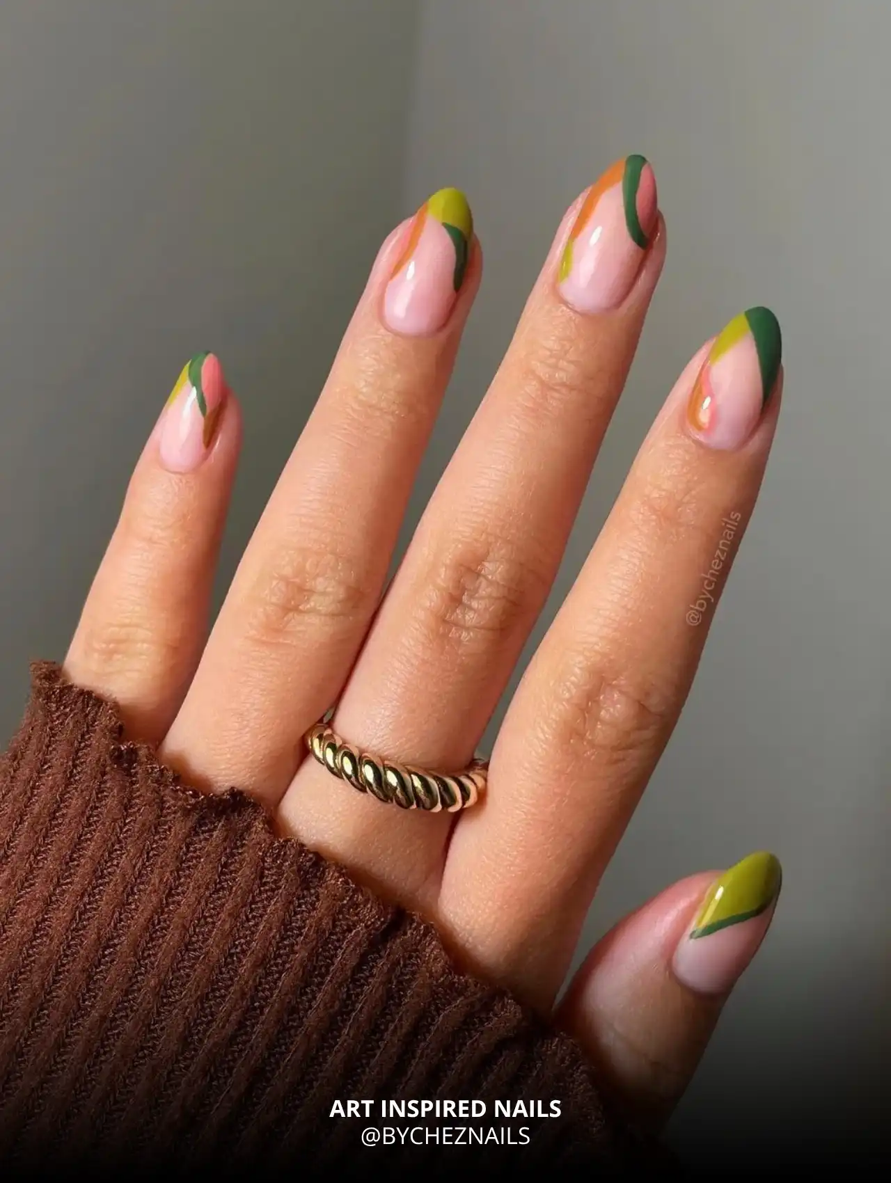 Art inspired fall nail design with green and orange abstract tips.