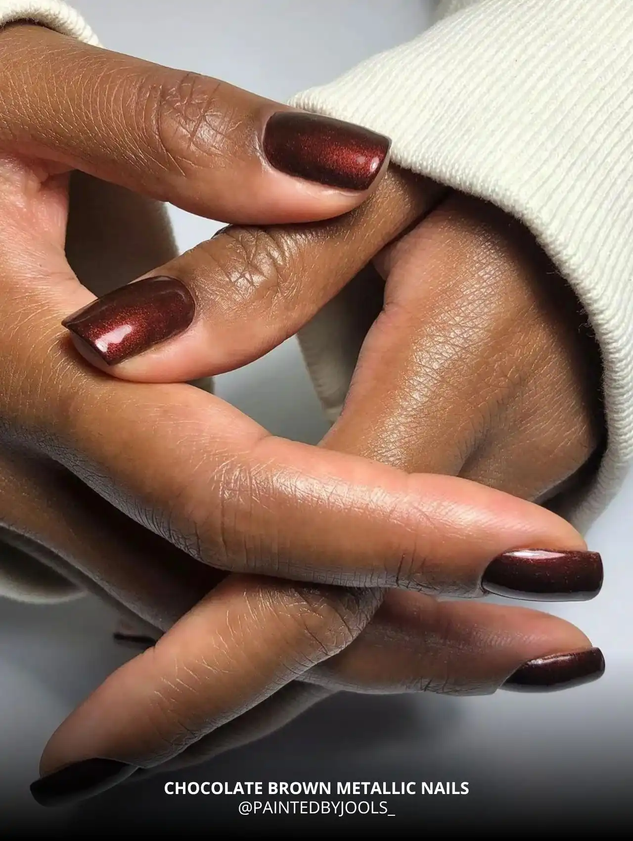Close-up of chocolate brown metallic fall nail design on dark skin