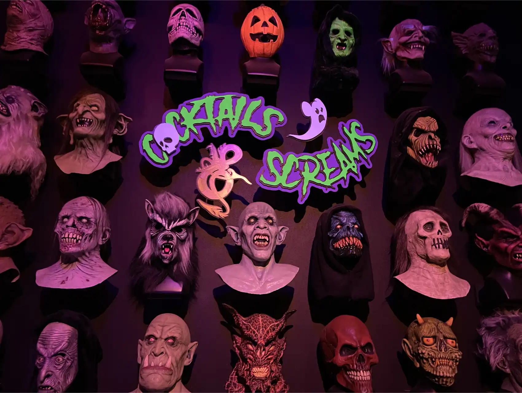 Wall of horror masks inside Cocktails & Screams bar in Orlando with neon signage, perfect for a halloween bar crawl.