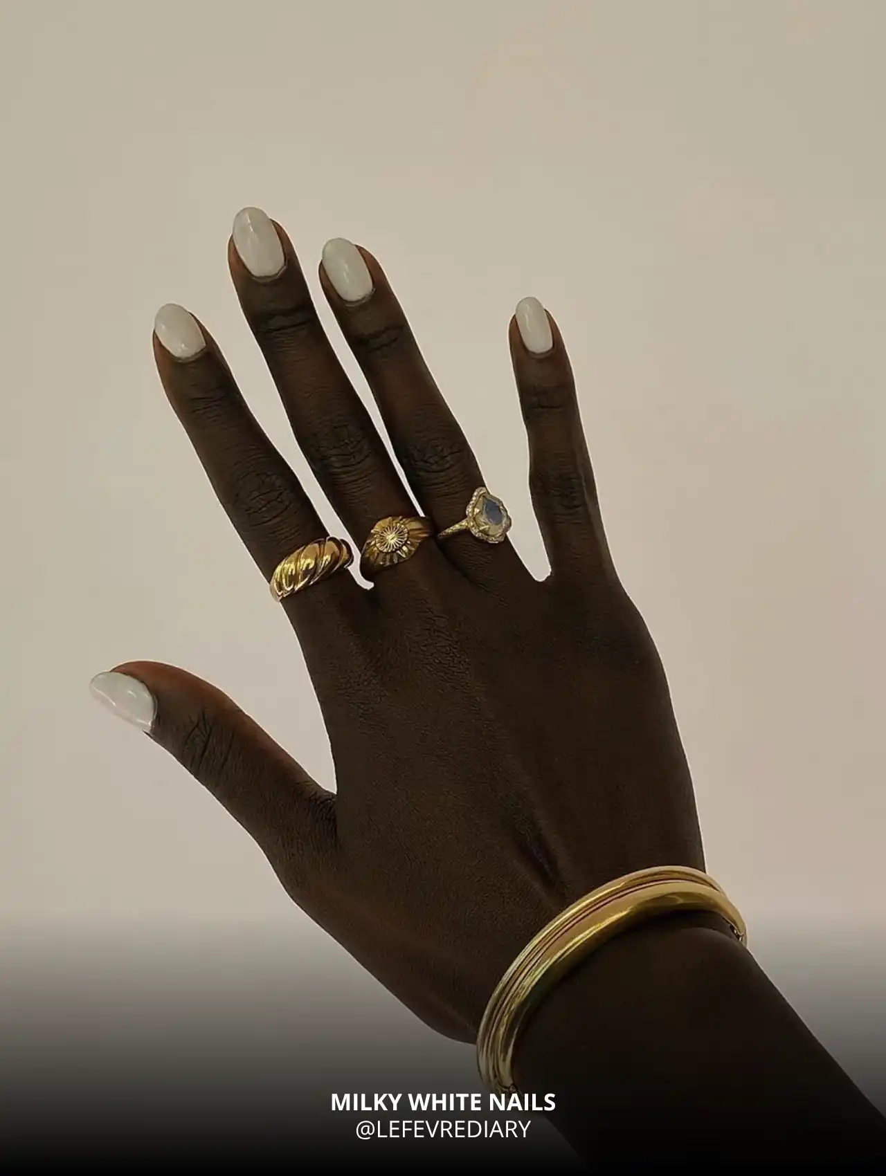 Milky white fall nail design with gold accessories on dark skin