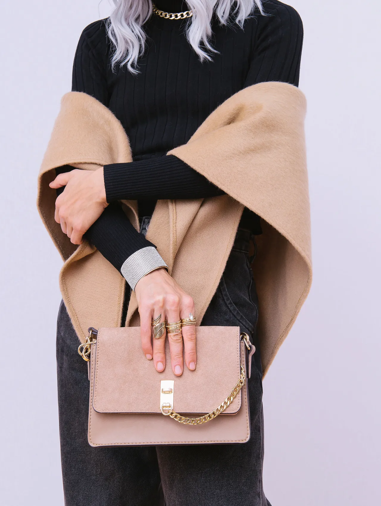 Imagen de ropa de invierno elegante con bolso beige y accesorios dorados, estilo ropa de invierno minimalista
