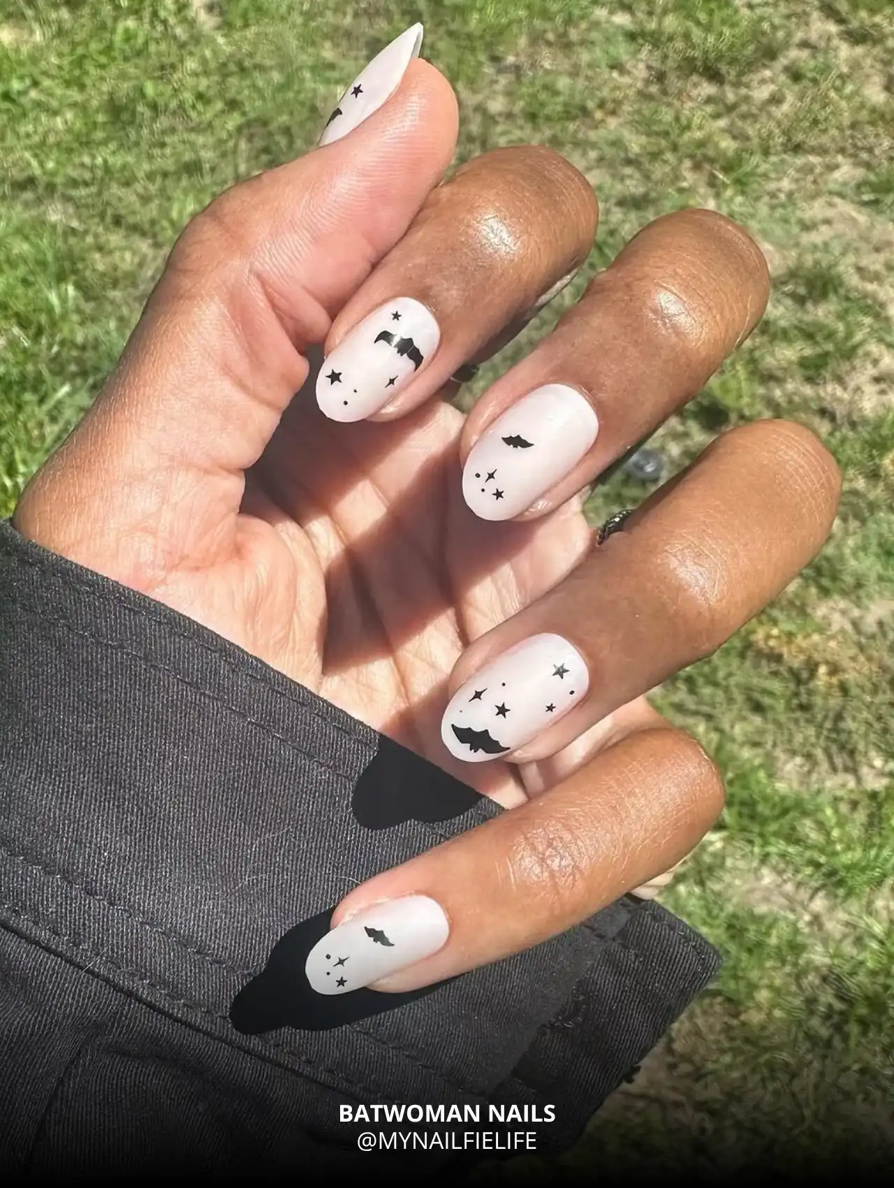 Batwoman Halloween nail art with black bats and stars on nude base, trendy Halloween nails