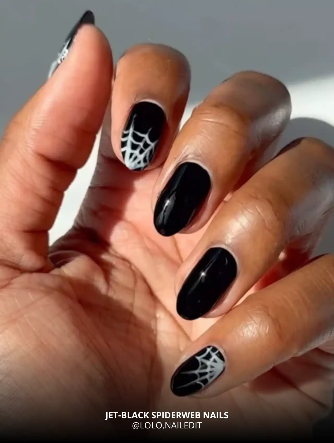 Jet-black nails with white spiderweb accents, trendy Halloween nails