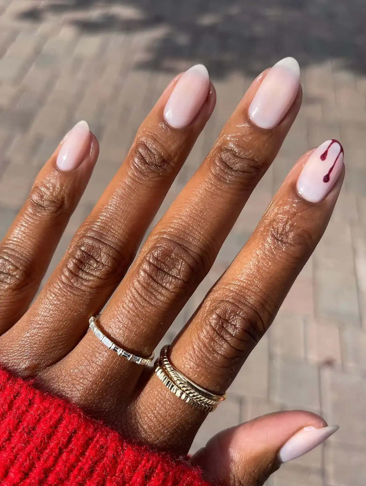 Minimalistic Halloween nails with nude polish and a subtle bloody drip design on the pinky finger.