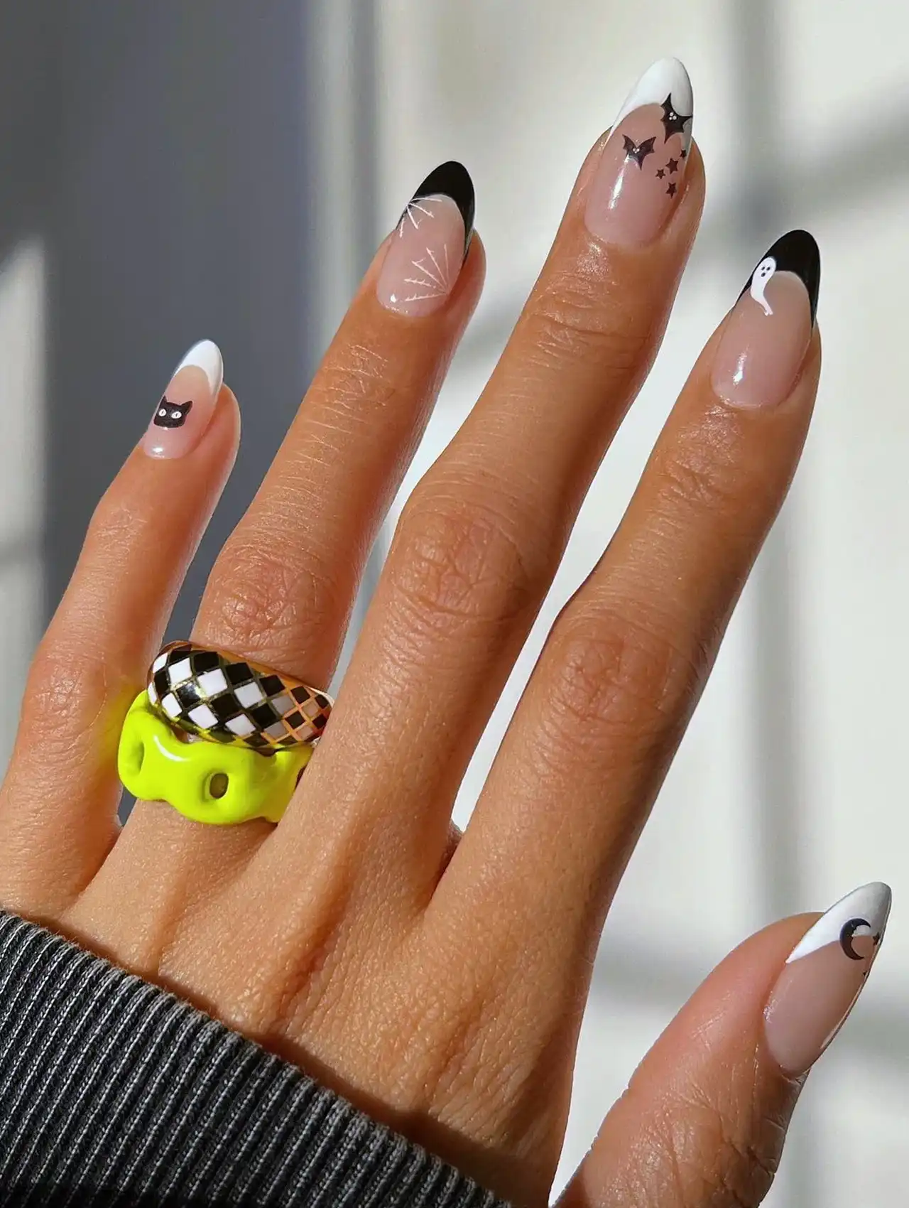 Minimalistic Halloween nails with black-and-white French tips and small spooky designs.