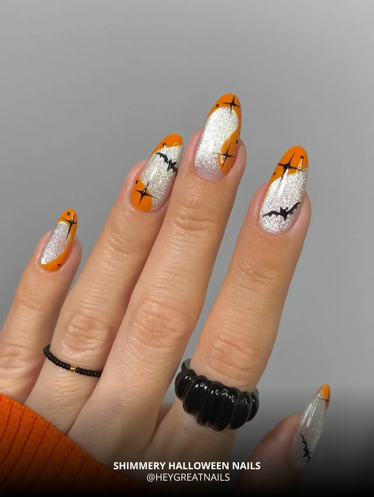 Glittery Halloween nails with orange tips and black bat accents, trendy Halloween nails