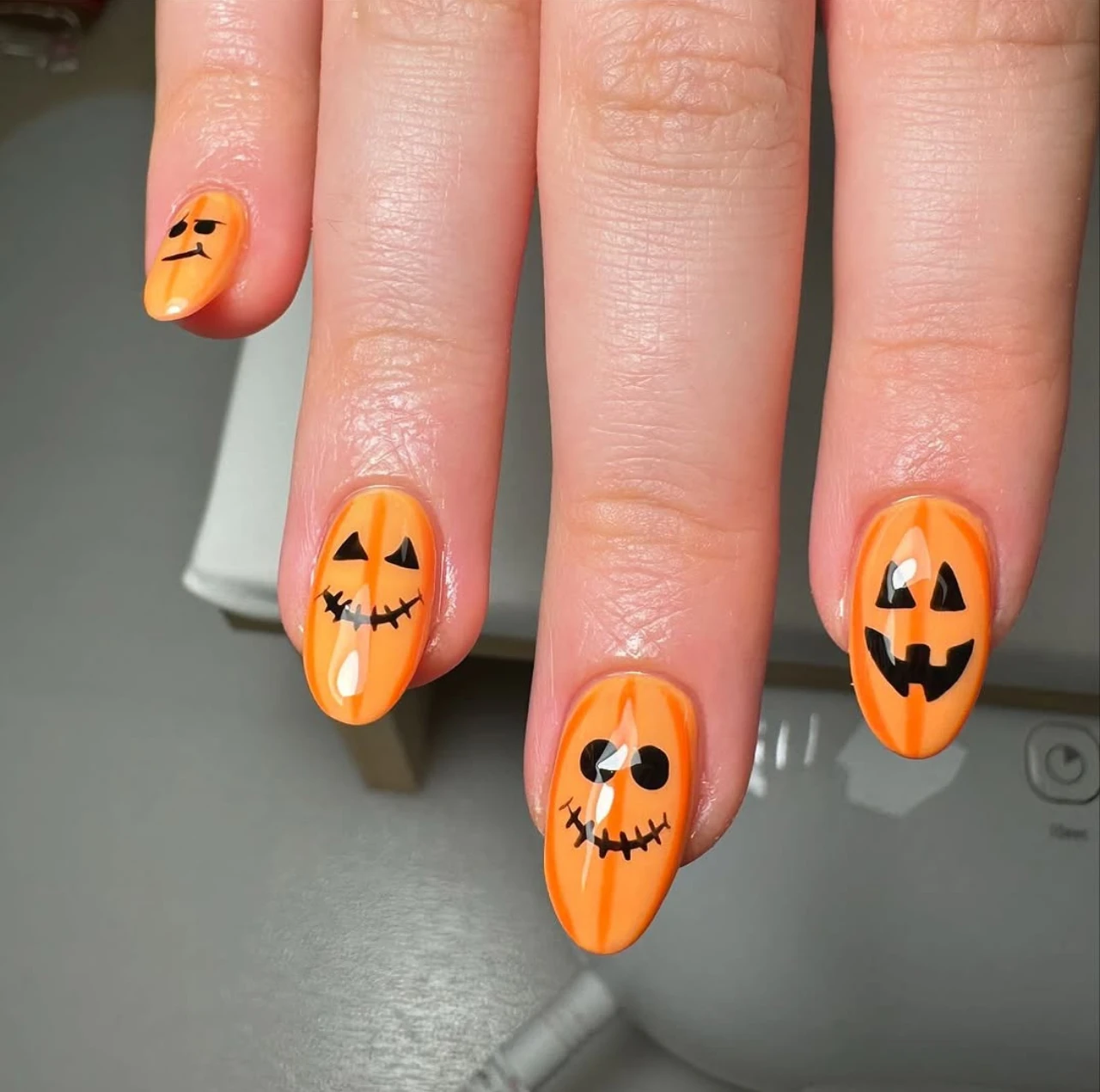 Diseño de uñas elegantes y sencillas con caritas de calabaza para Halloween.