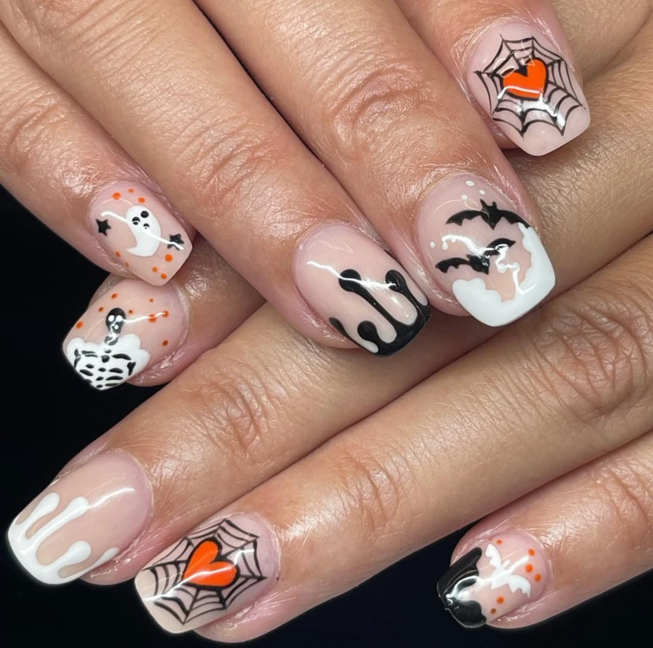 Diseños de uñas elegantes y sencillas en formato corto con fantasmas, murciélagos, telarañas y detalles en blanco y negro.