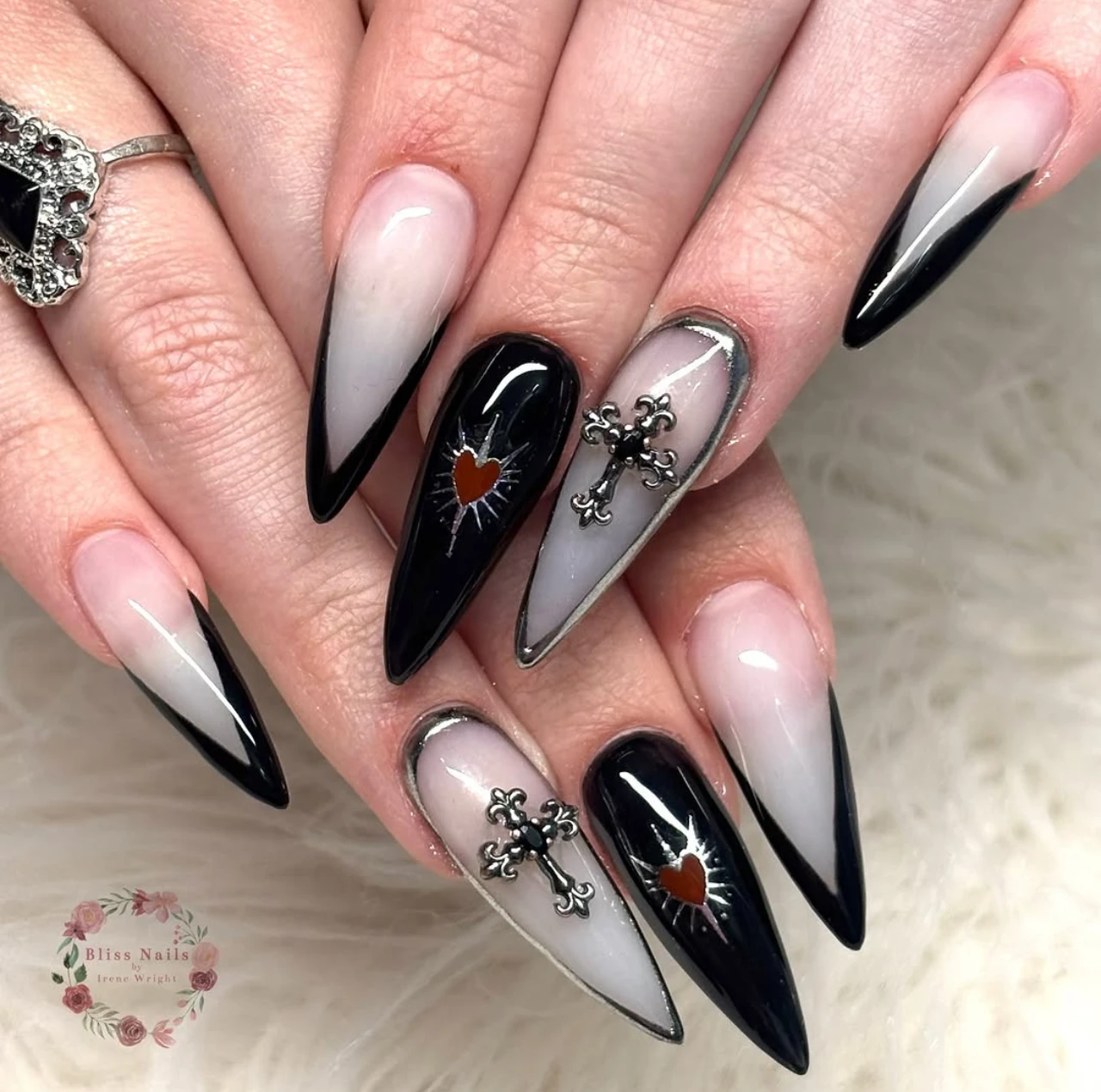 Diseño de uñas elegantes y sencillas con estilo gótico, corazones metálicos, cruces y punta negra en forma stiletto.