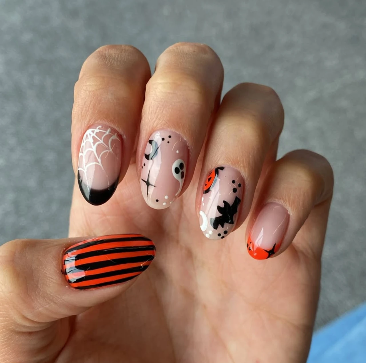 Diseño de uñas elegantes y sencillas con patrones de Halloween: telarañas, fantasmas, murciélagos y rayas.