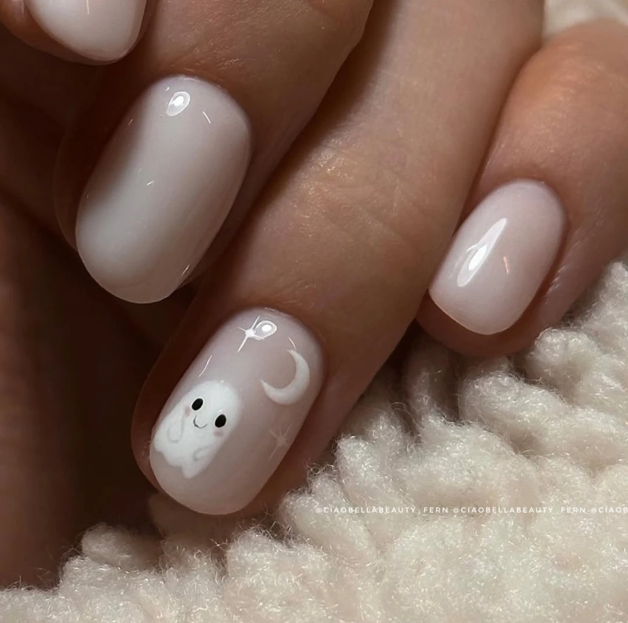 Diseño de uñas elegantes y sencillas con fantasmitas blancos sobre base nude para Halloween.