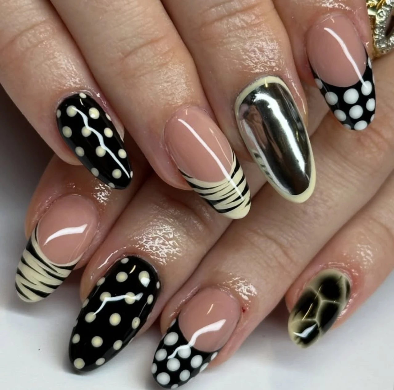 Uñas en tendencia otoño con diseño abstracto en blanco, negro y acabado cromado.