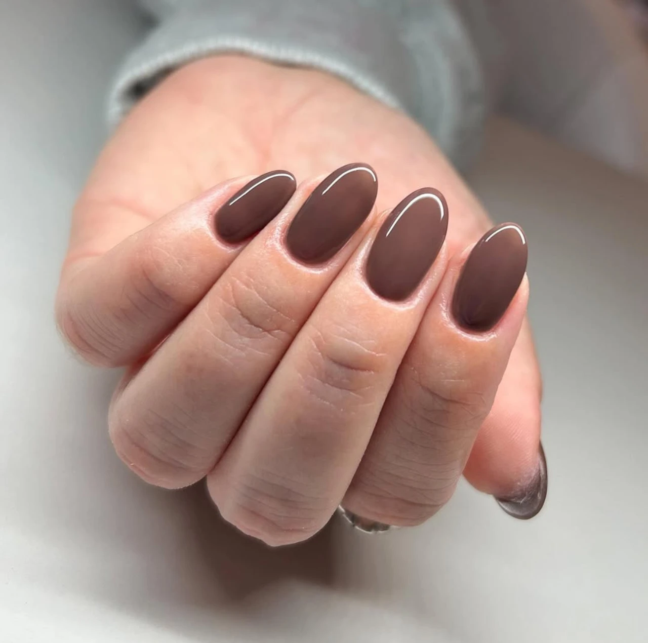 Uñas en tendencia otoño en tono espresso con acabado brillante y forma almendrada.