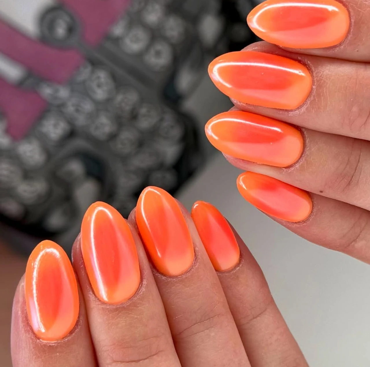 Uñas en tendencia otoño en tono naranja cromado con acabado brillante y moderno.