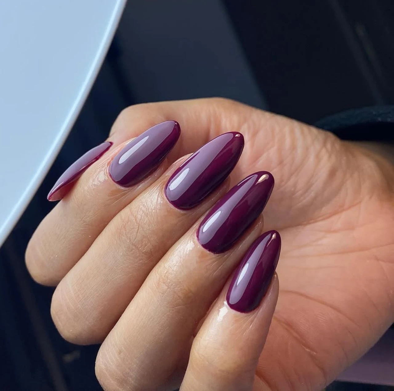Uñas en tendencia otoño en tonos morados intensos con acabado brillante y elegante.
