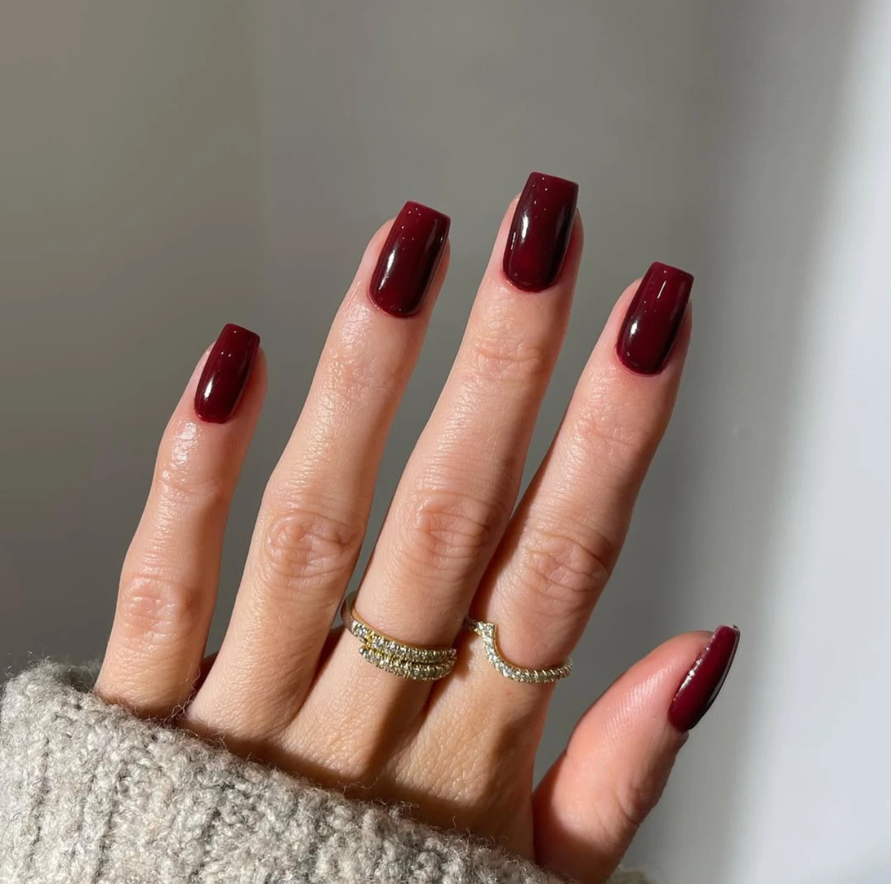 Uñas en tendencia otoño en tono vino tinto con acabado brillante y forma cuadrada.