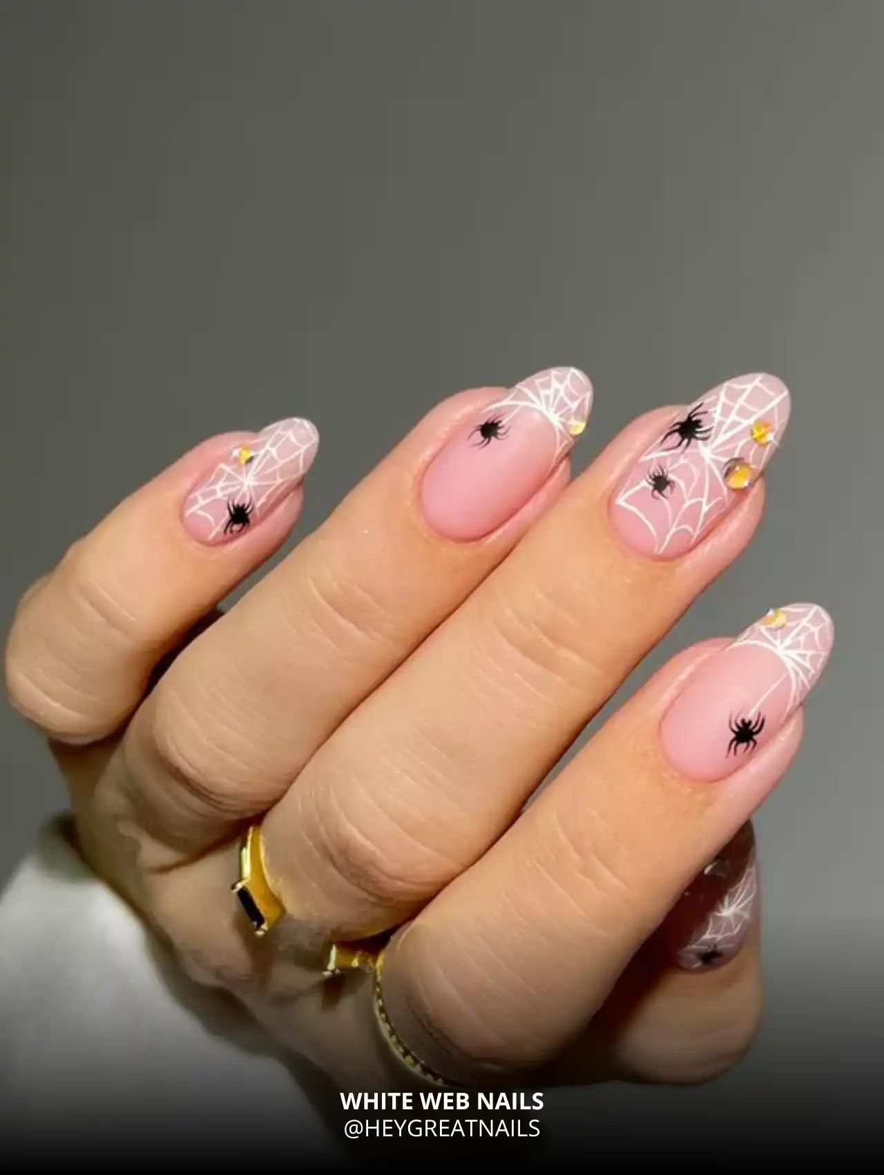 Light pink base nails with white spiderwebs and small black spiders, trendy Halloween nails