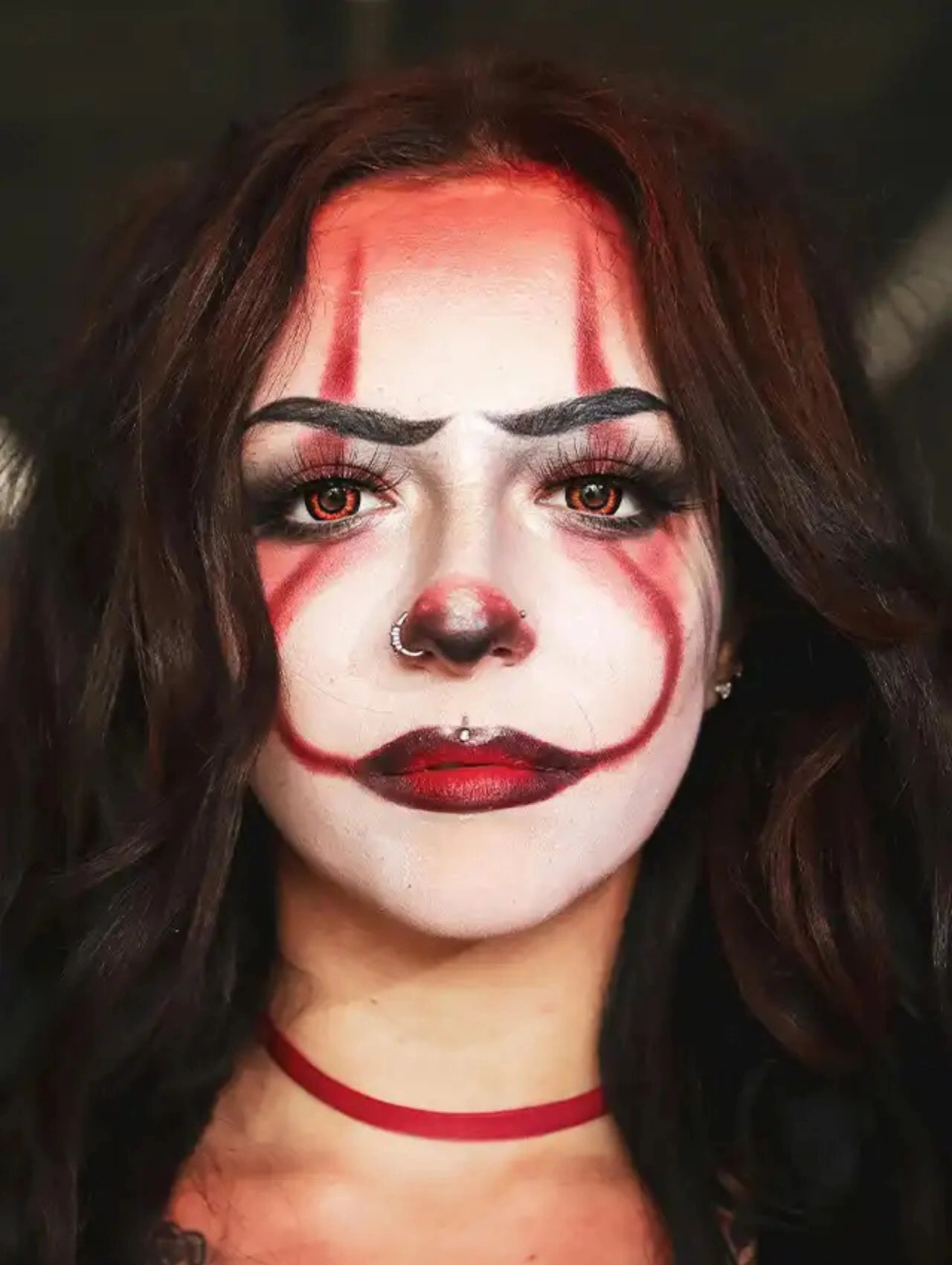 Maquillaje de payaso para Halloween con detalles en rojo y blanco, ideal para un look terrorífico y creativo.