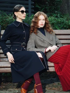 Dos mujeres con atuendos elegantes mostrando outfits para invierno con abrigos largos y faldas, representando las tendencias más sofisticadas de la temporada.