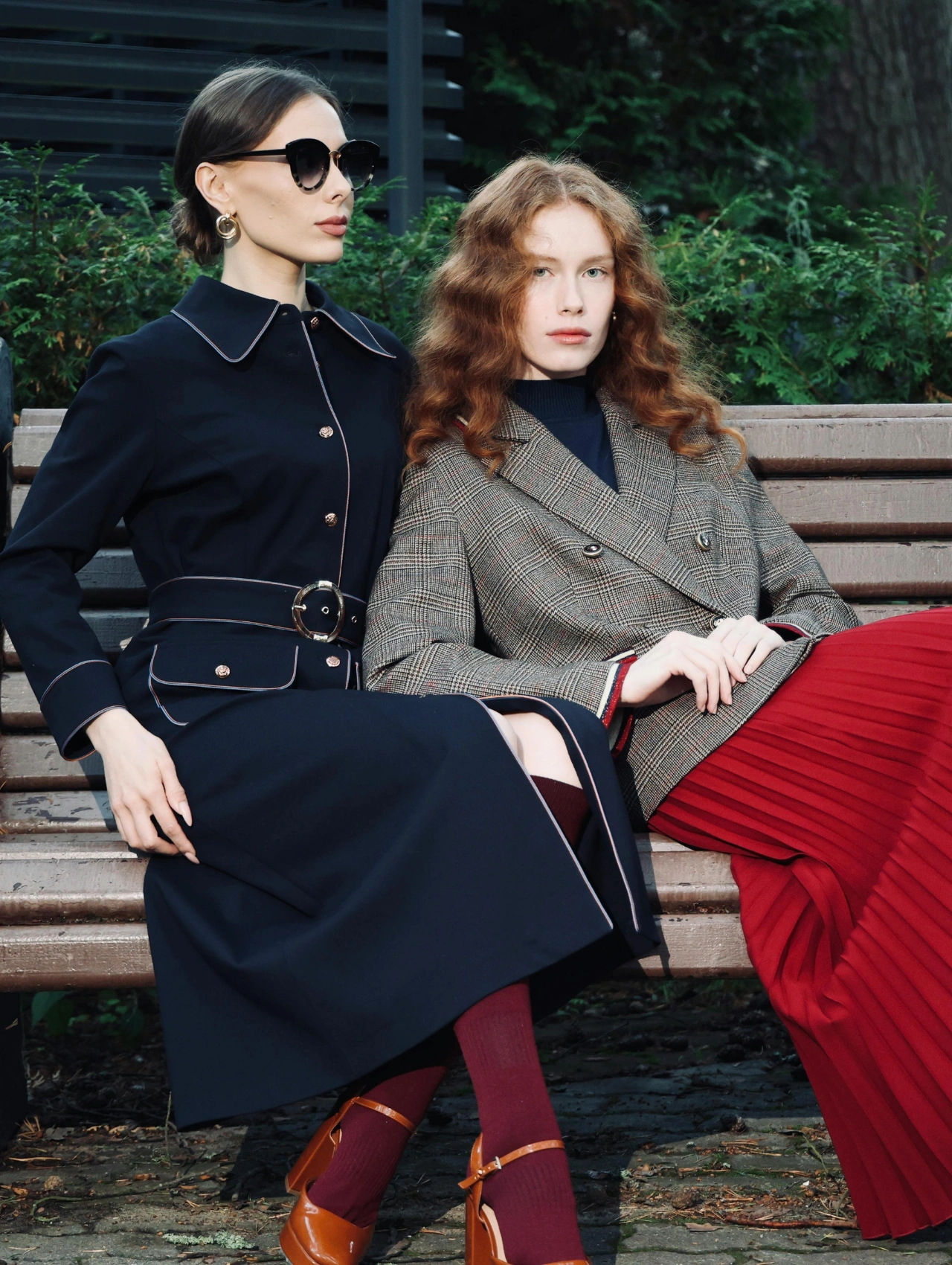 Dos mujeres con atuendos elegantes mostrando outfits para invierno con abrigos largos y faldas, representando las tendencias más sofisticadas de la temporada.