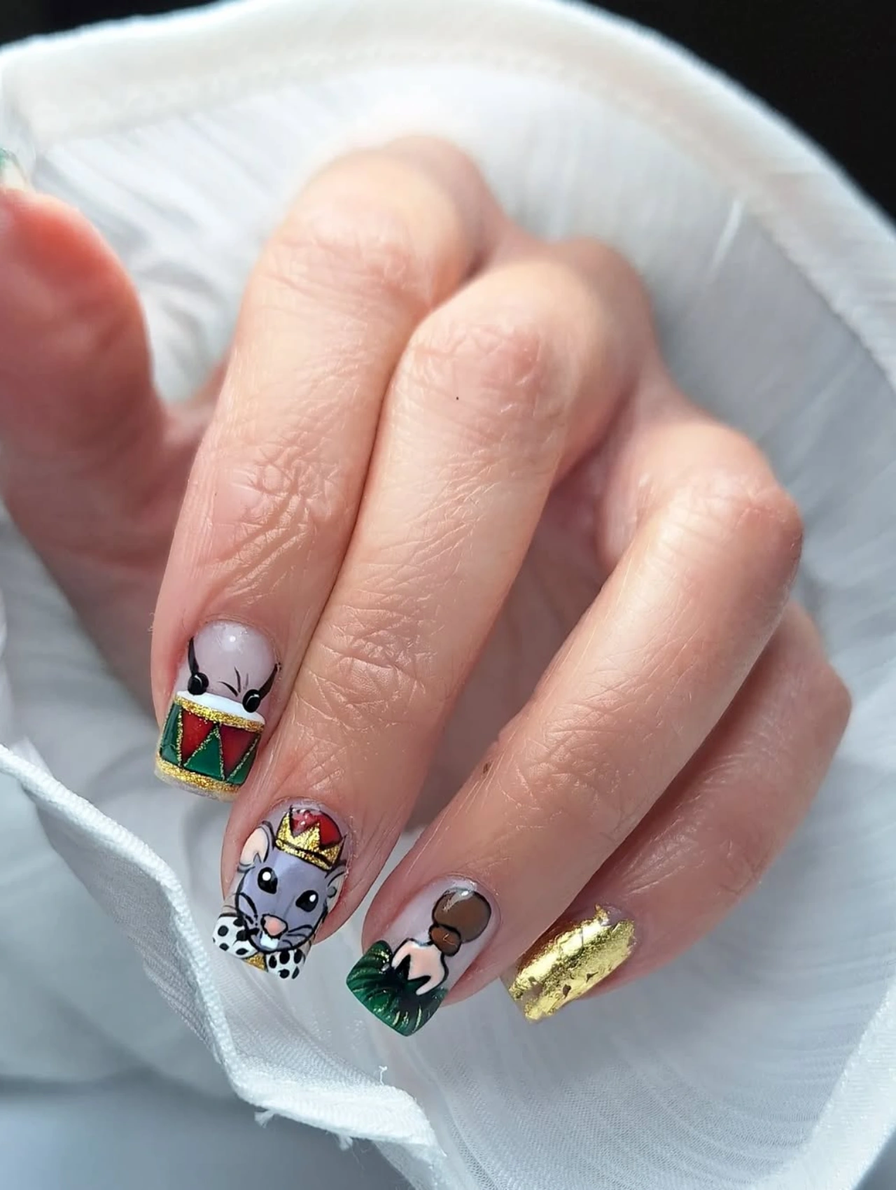Diseños de uñas para invierno con temática de cascanuez y personajes navideños pintados a mano