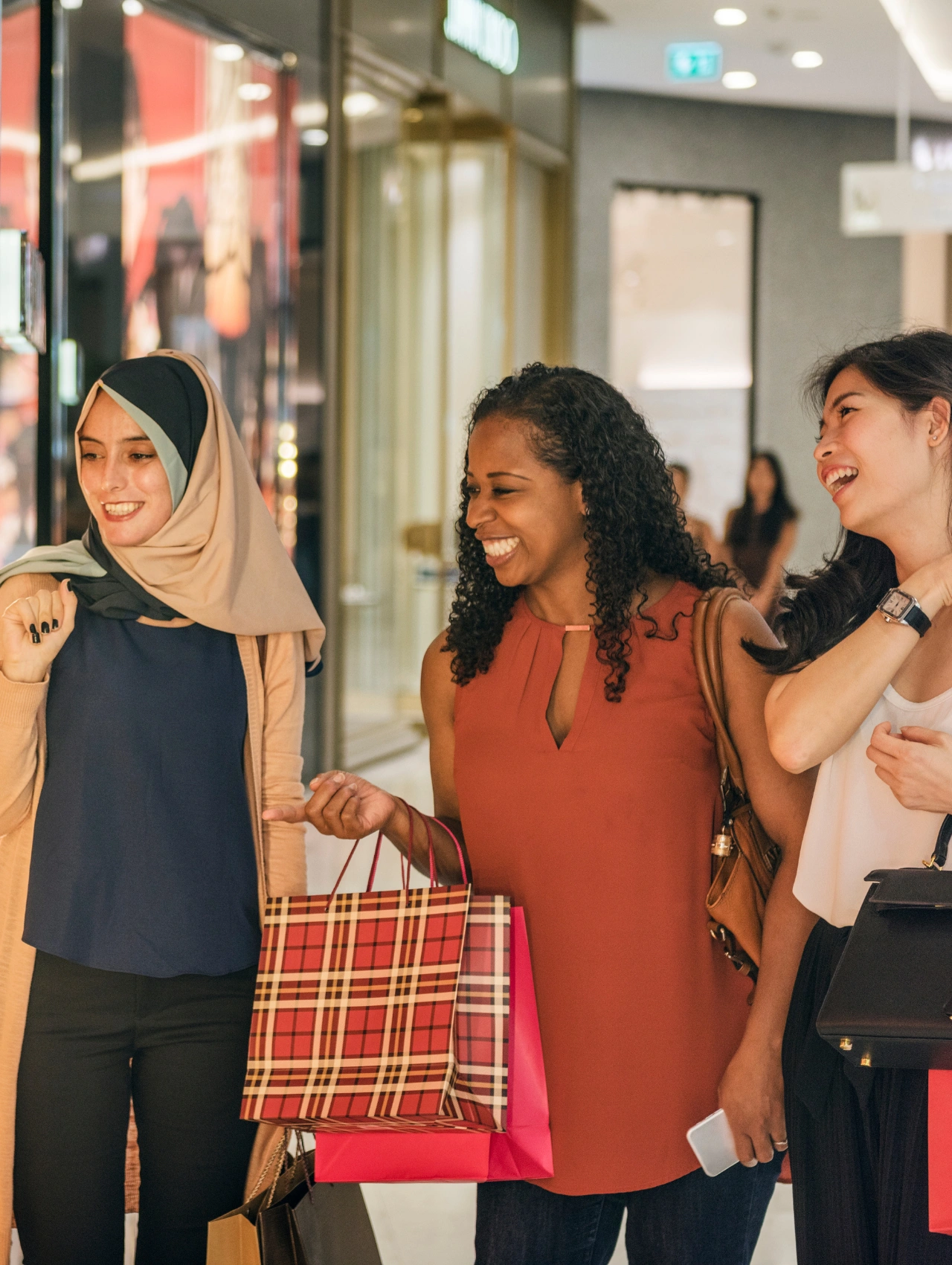 Women smiling and shopping at a mall during Ulta Black Friday Sales with shopping bags and a festive retail atmosphere.