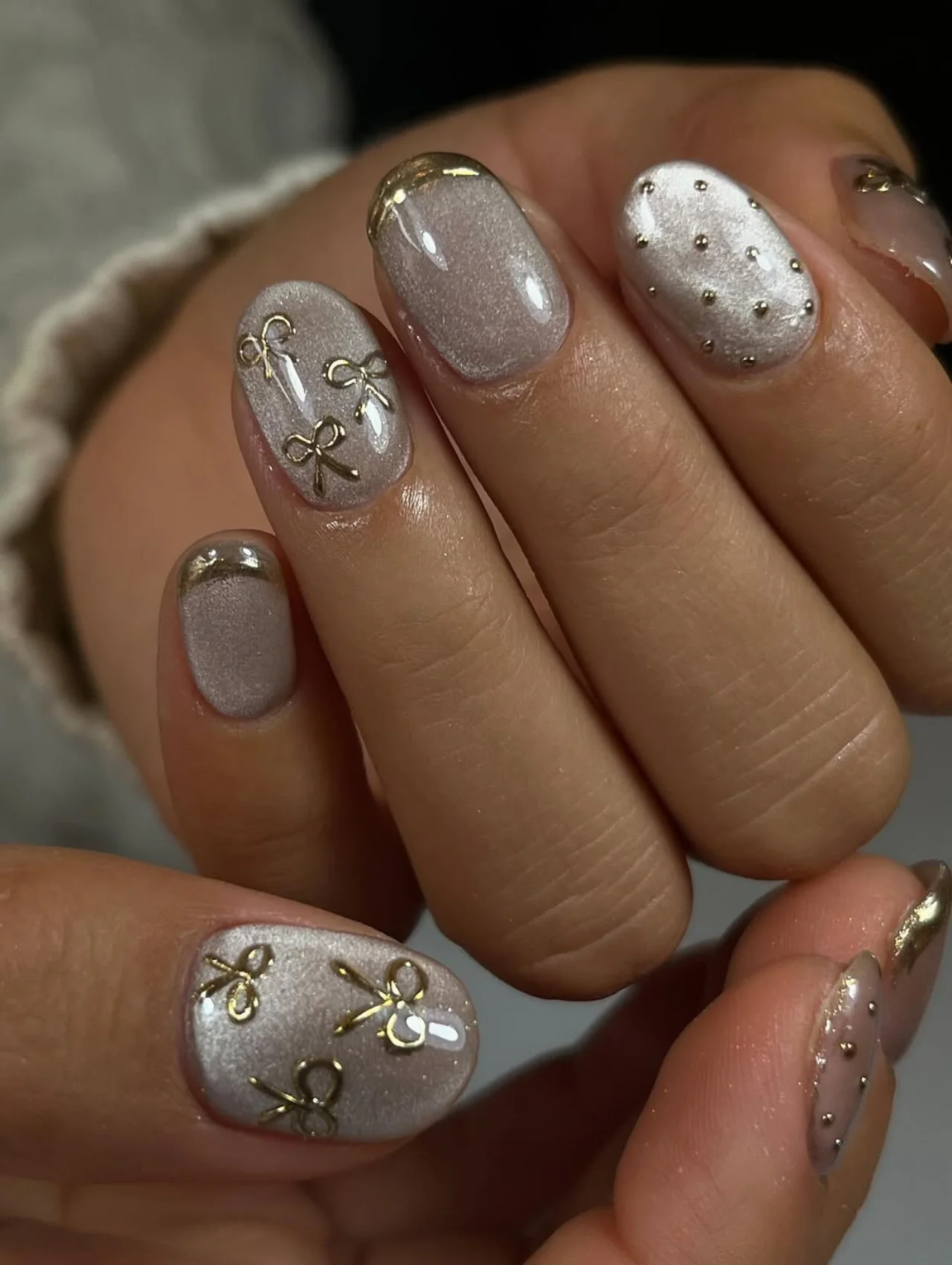 Diseños de uñas para invierno con moños dorados estilo coquette