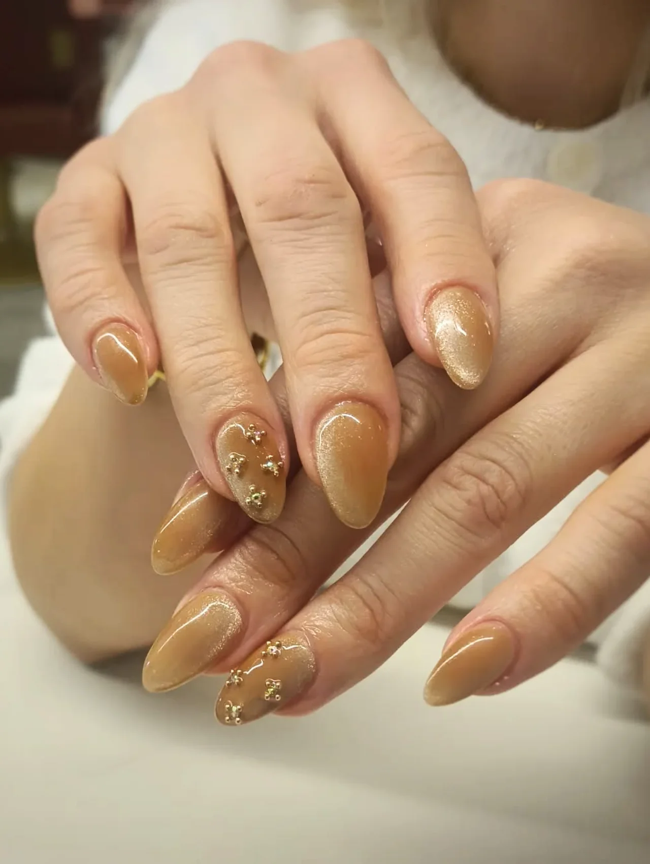 Diseños de uñas para invierno en tonos champaña con brillo y decoración de cristales