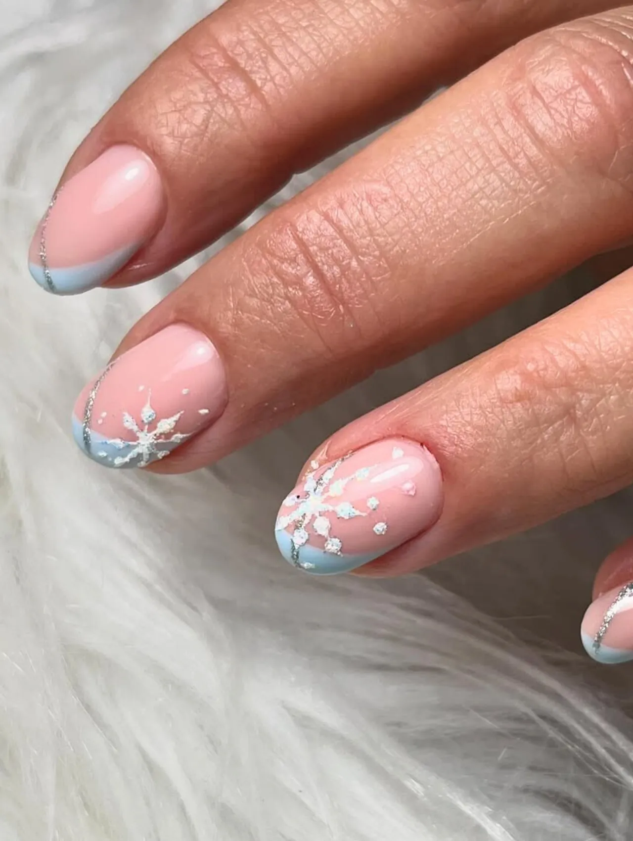 Diseño de uñas para invierno con copos de nieve blancos sobre base rosa